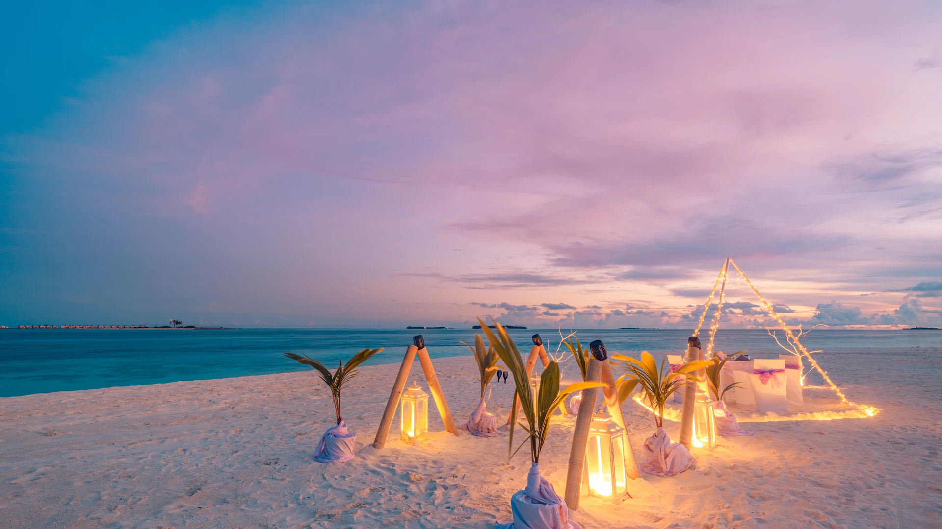Private beach dinner set on the sand at sunset